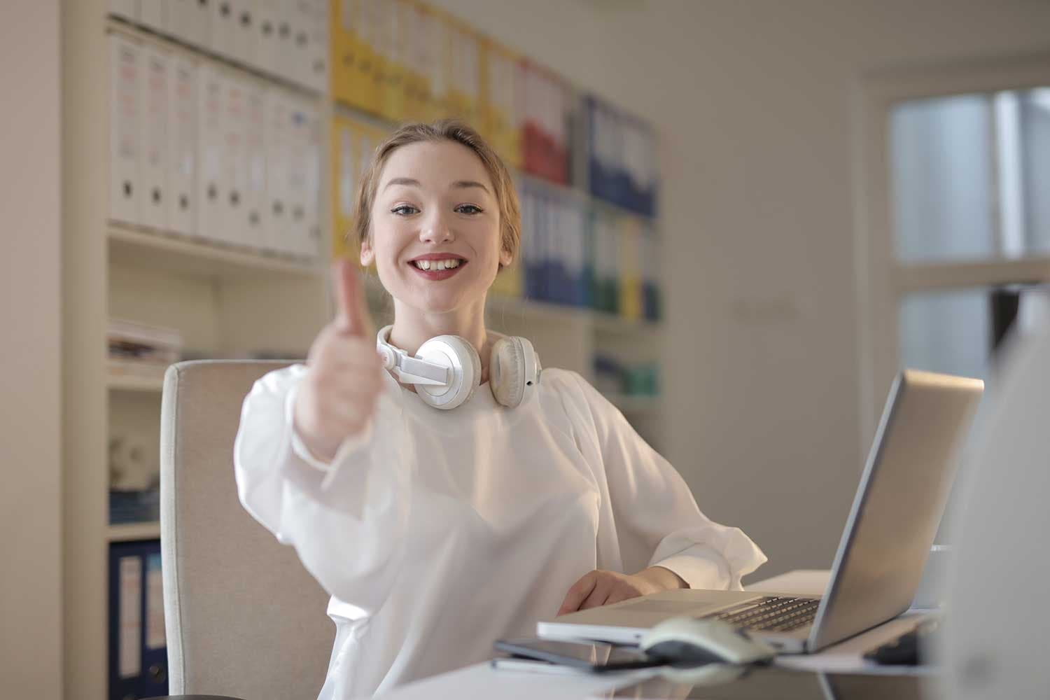 Professional smiling and giving a thumbs up at her desk